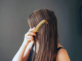 woman combing long hair with wooden comb