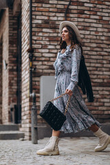 a beautiful young woman in a hat and a blue dress walks through the city. walk, shopping