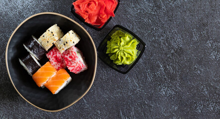 Sushi rolls with wasabi, ginger on dark background with copy space on the right