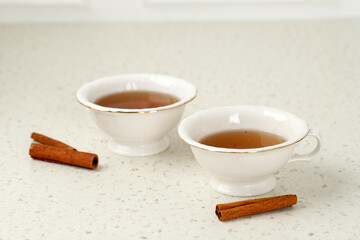 Glass cup of tea with cinnamon sticks. White background. Isolated.