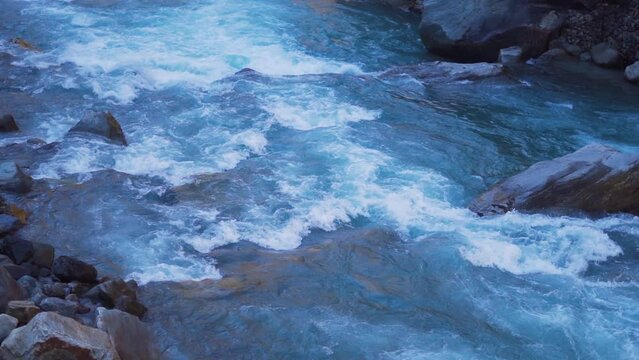 Slow motion shot of the Paravti River flowing in between mountains at Kasol in Himachal Pradesh, India. View of the Parvati river during the winter. Natural river in the mountains background.