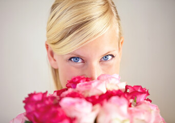 Fototapeta premium Another present from her secret admirer. Portrait of a young woman peering over a bouquet of pink roses.