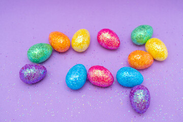Fototapeta na wymiar Multi-colored Easter eggs on a purple background. Holiday concept with copy space.