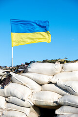 Ukrainian flag blue yellow color flutters in blue sky on barricades. Ukraine Russia War 2022....