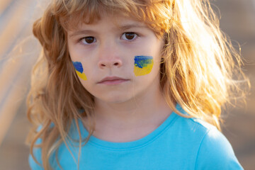 Ukraine flag on kids cheek. No war, stop war, russian aggression. Little ukrainian patriot.