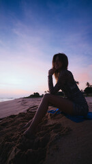 Girl sitting on a sand on the sunset