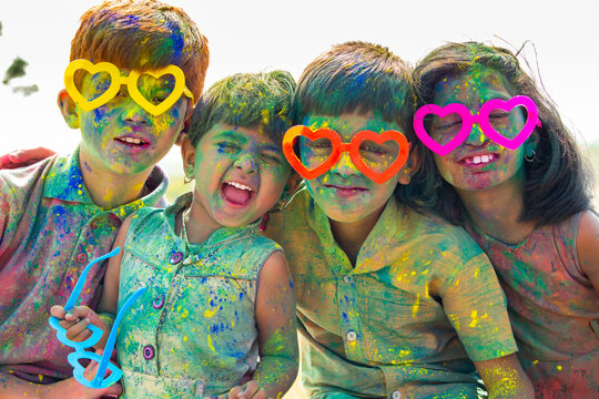 Group of Cheerful kids with fun spectacles Shouting at camera after playing with colourful holi powder during festival celebration.