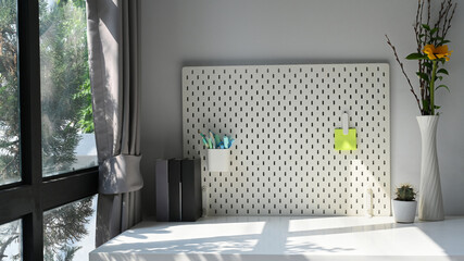 Pegboard with stationery and sticky note on white table in living room.