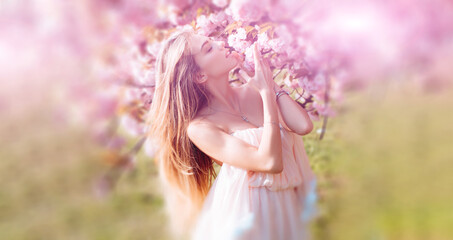 Beautiful spring young woman outdoors enjoying spring. Beautiful young woman near blooming spring tree. Youth, love, fashion, romantic and lifestyle concept.