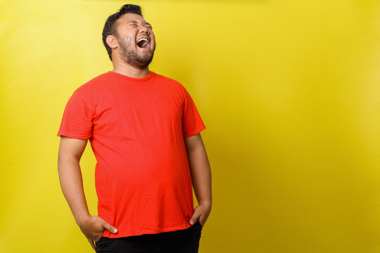 Asian Fat Man In Red Tshirt Laugh Out Loud  Isolated On Yellow Background 