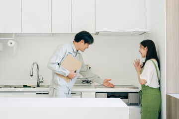 キッチンで話す作業着姿の男性と女性（IH・笑顔）
