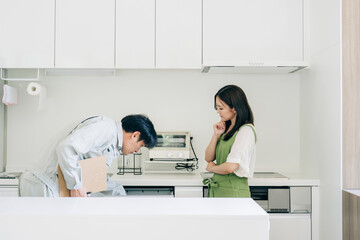 キッチンで話す作業着姿の男性と女性（食洗機・困る）
