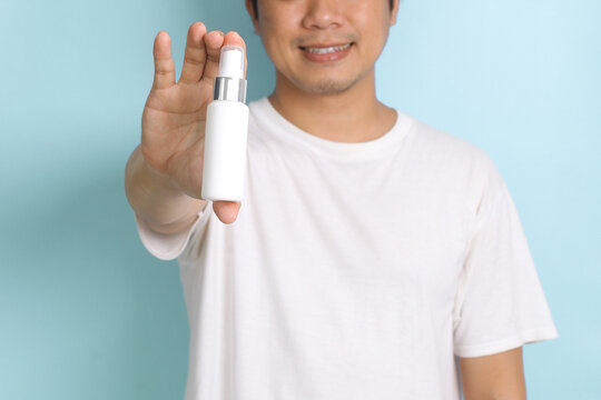 Cropped Of Man Showing Spray Bottle Packaging To Camera For Mock Up Isolated On Pastel Blue Background