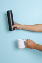 Hand holding black thermos and mug for mock up. Insert your text  or brand