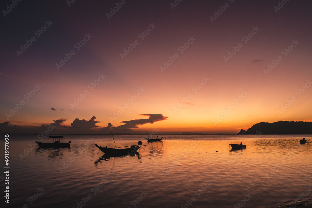 Wall mural silhouettes of fishing boats on the sea at a beautiful sunset