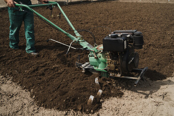 Modern farming, technology agriculture. Gardener man cultivate ground soil with tiller tractor or...
