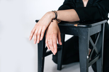 The woman's hands, folded one on top of the other, hang from the chair