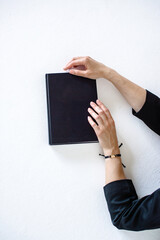 Women's hands are lying on a black book