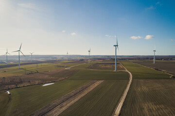 Turbiny wiatrowe, wiatraki produkują energię odnawialną z wiatru na pięknych malowniczych polach oświetlone słońcem - obrazy, fototapety, plakaty
