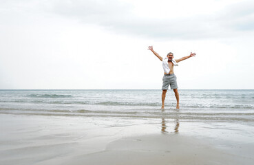 A happy senior man jumping on the beach in the sea water ......
