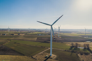 Fototapeta Turbiny wiatrowe, wiatraki produkują energię odnawialną z wiatru na pięknych malowniczych polach oświetlone słońcem obraz