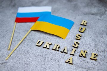 selective focus side view of the flags Russia Ukraine and the inscriptions on a gray concrete background, the concept of peace, goodness, love, freedom and friendship of fraternal peoples
