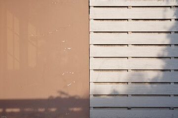 Grunge and aged brown concrete wall with White wooden plank with shadow from shade of tree in...