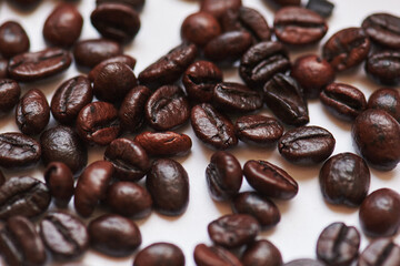 oily roasted coffee beans on white background close-up