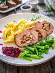 Stuffed pork minced meat with mushrooms, potato puree and green beans on wooden table