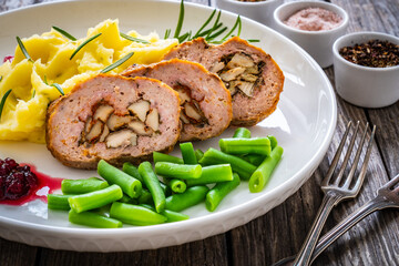 Stuffed pork minced meat with mushrooms, potato puree and green beans on wooden table