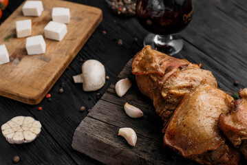 homemade hot-smoked chicken thighs, in on an old wooden board next to vegetables and spices