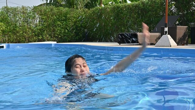 Asian woman drowning in swimming pool caused of cramp occur on her legs. Leg cramps happen when a muscle in the leg shortens and causes a sudden pain that can make it hard to move.