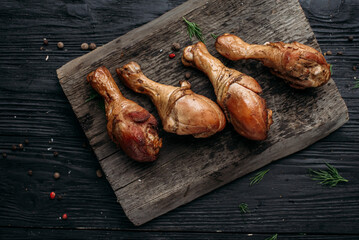 smoked homemade chicken drumstick on a wooden background and an old wooden hot smoked stick