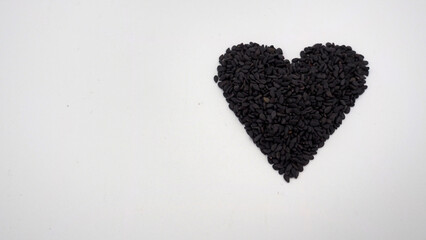 Black sesame seeds in heart shape on white background.It is asian food.