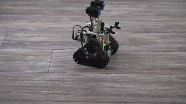 The robot from the children's designer on the control panel. DIY educational toy. A radio-controlled robot rides on the floor. Robotics in action.