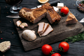 Smoked rib, home-smoked on a wooden background next to vegetables and spices
