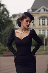 Retro portrait of beautiful European woman in black dress, with big red lips, retro hairdress and...