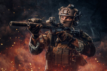 Army soldier with rifle aiming against dark flaming background