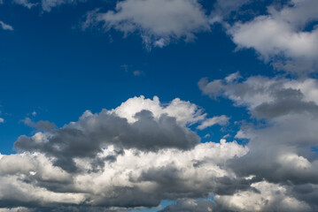 Fototapeta na wymiar Jasne i ciemne chmury na tle niebieskiego nieba.