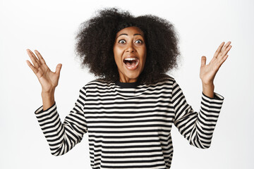Enthusiastic african american woman celebrating, scream yes, looking amazed and surprised, winning,...