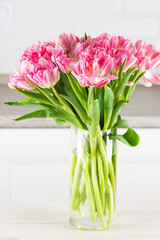 Bouquet of pink tulips in a vase on the table.