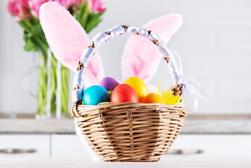 Basket with Easter eggs and bunny ears on a background of flowers.