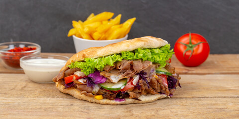 Döner Kebab Doner Kebap fast food in flatbread with fries on a wooden board panorama