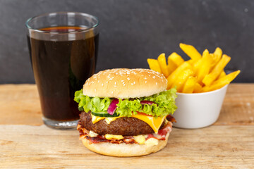 Hamburger Cheeseburger meal fastfood fast food with cola drink and French Fries on a wooden board