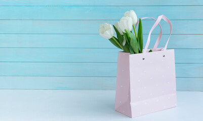 Bouquet of white tulips in a pink gift bag