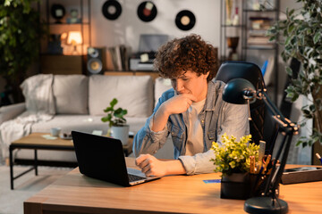 A man sits thoughtfully in front of a latop on a leather chair. He is having trouble logging into his internt account. He is thinking how to solve this problem.