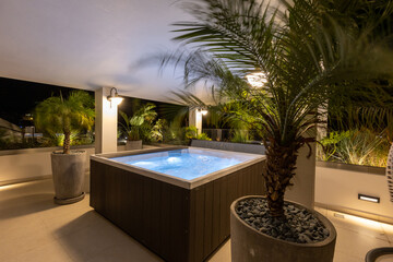 Illuminated hydromassage bathtub on the hotel terrace in the evening