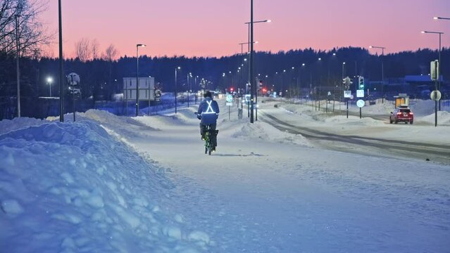 The man on a bicycle in a winter evening. Light is reflected from clothing reflectors and bicycle wheels. Safe cycling in the dark time.