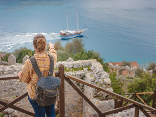 Fototapeta premium Travel and tourist attractions at Kekova island, Turkey. Woman traveler explores ruins castle of Simena with view of sea bay and Kekova Island with famous flooded city. Tourist attractions in Turkey.