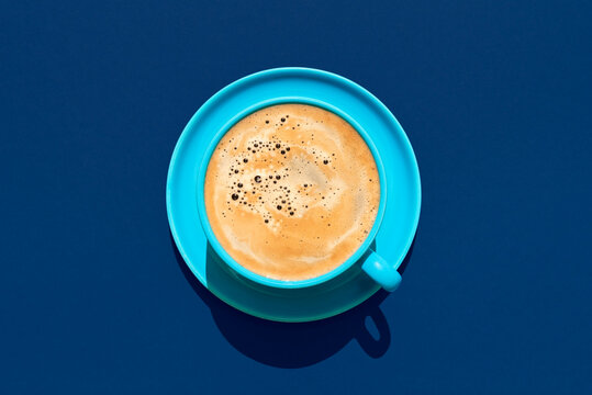 Cup of coffee above view on a blue background. Hot coffee in a blue mug.